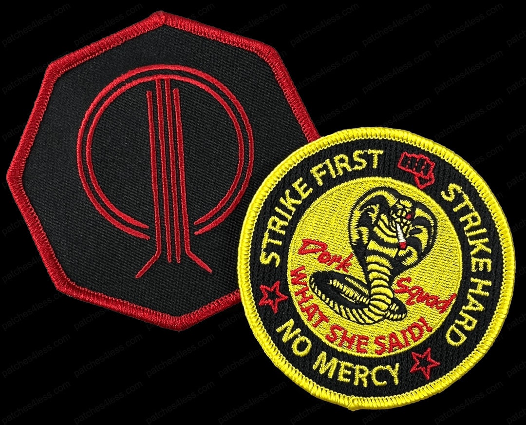 Two airsoft patches. One is a red and black octagonal patch with a stylized design, and the other is a yellow and black circular patch with a cobra emblem and the text 'Strike First, Strike Hard, No Mercy' along with 'Dojo Squad What She Said!'