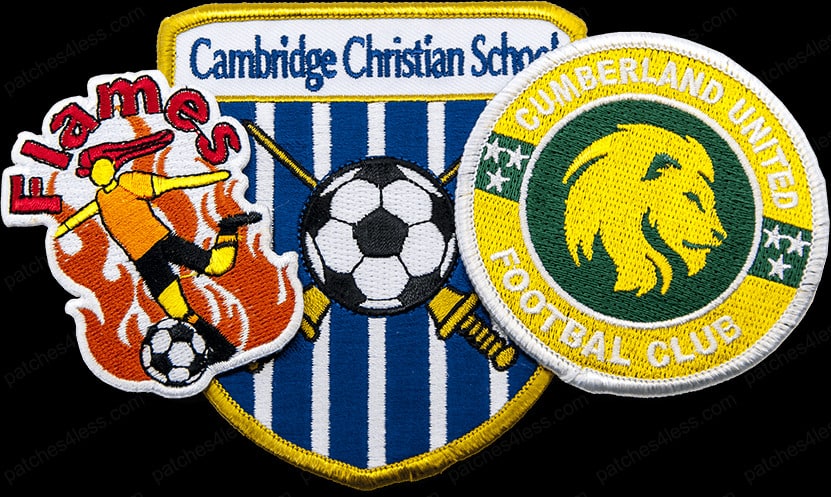 Three soccer team patches. One reads 'Flames' with a player kicking a ball in front of flames, another is a shield-shaped patch with blue and white stripes and the text 'Cambridge Christian School' with a soccer ball, and the third is a circular patch with a lion and the text 'Cumberland United Football Club'.